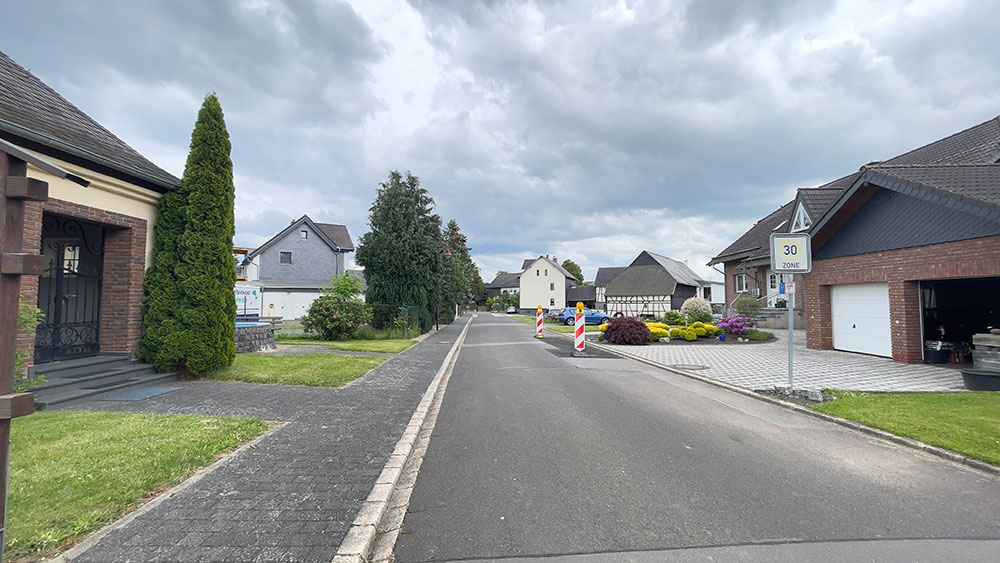 Ruhige Wohnstraße in einer Tempo-30-Zone mit Einfamilienhäusern und Vorgärten.